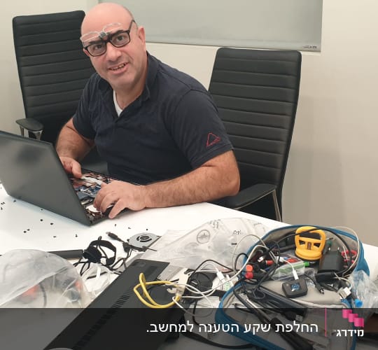 אדם מתקן מחשב נייד עם כלים על שולחן